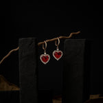 Heart-shaped red gemstone earrings on a dark background