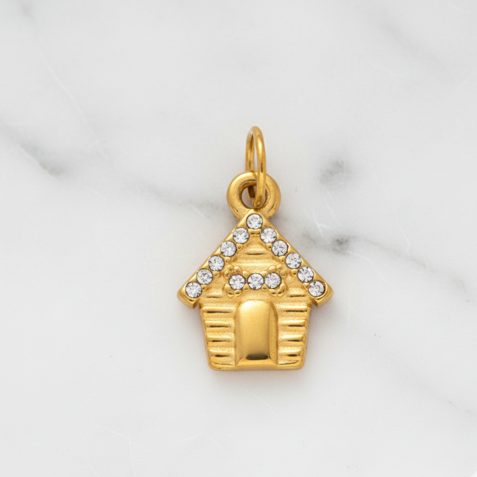 Gold doghouse charm with crystals on a marble background