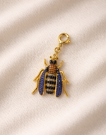 Bejeweled beetle charm on a beige fabric background