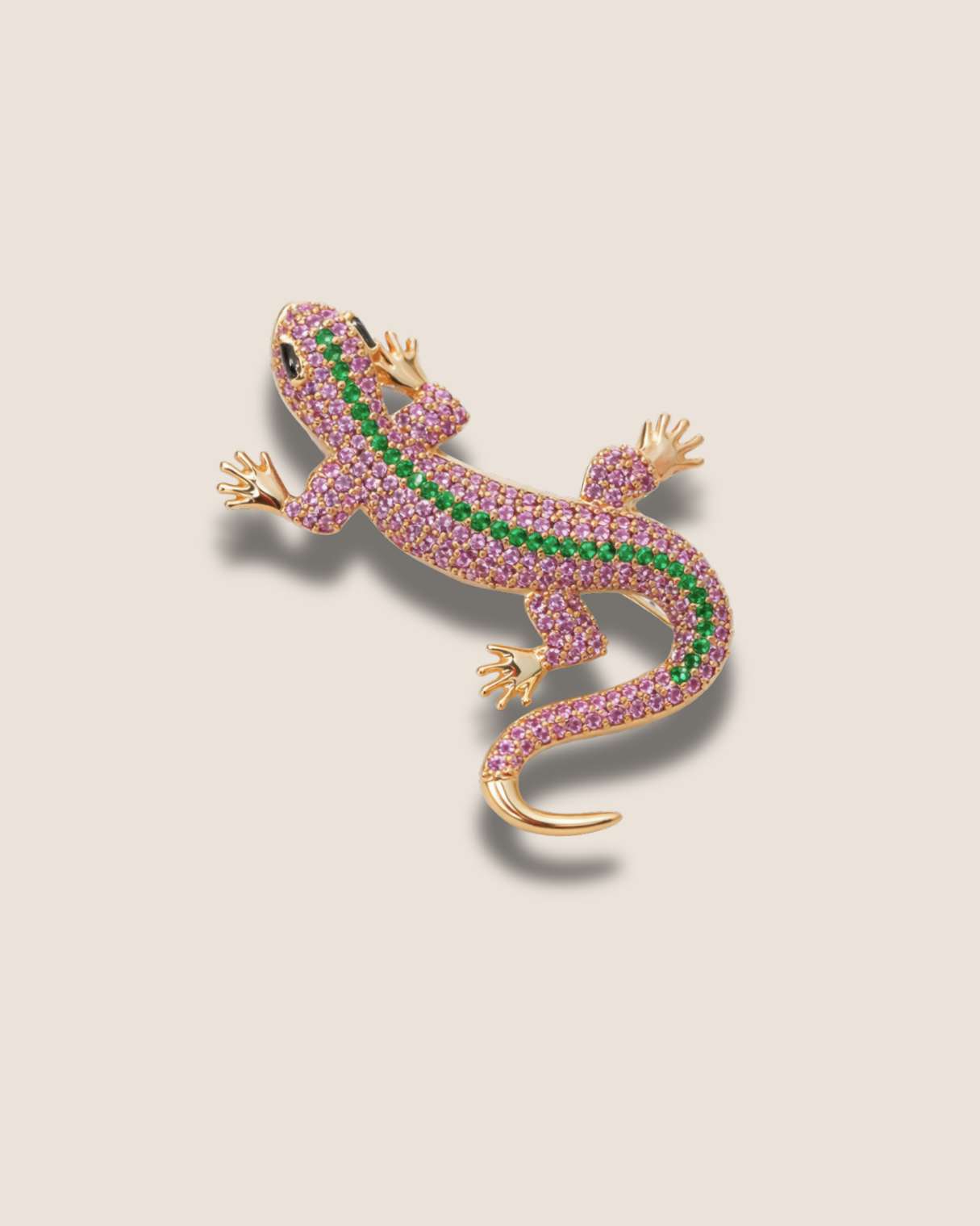 Jeweled lizard brooch with pink and green stones on a beige background