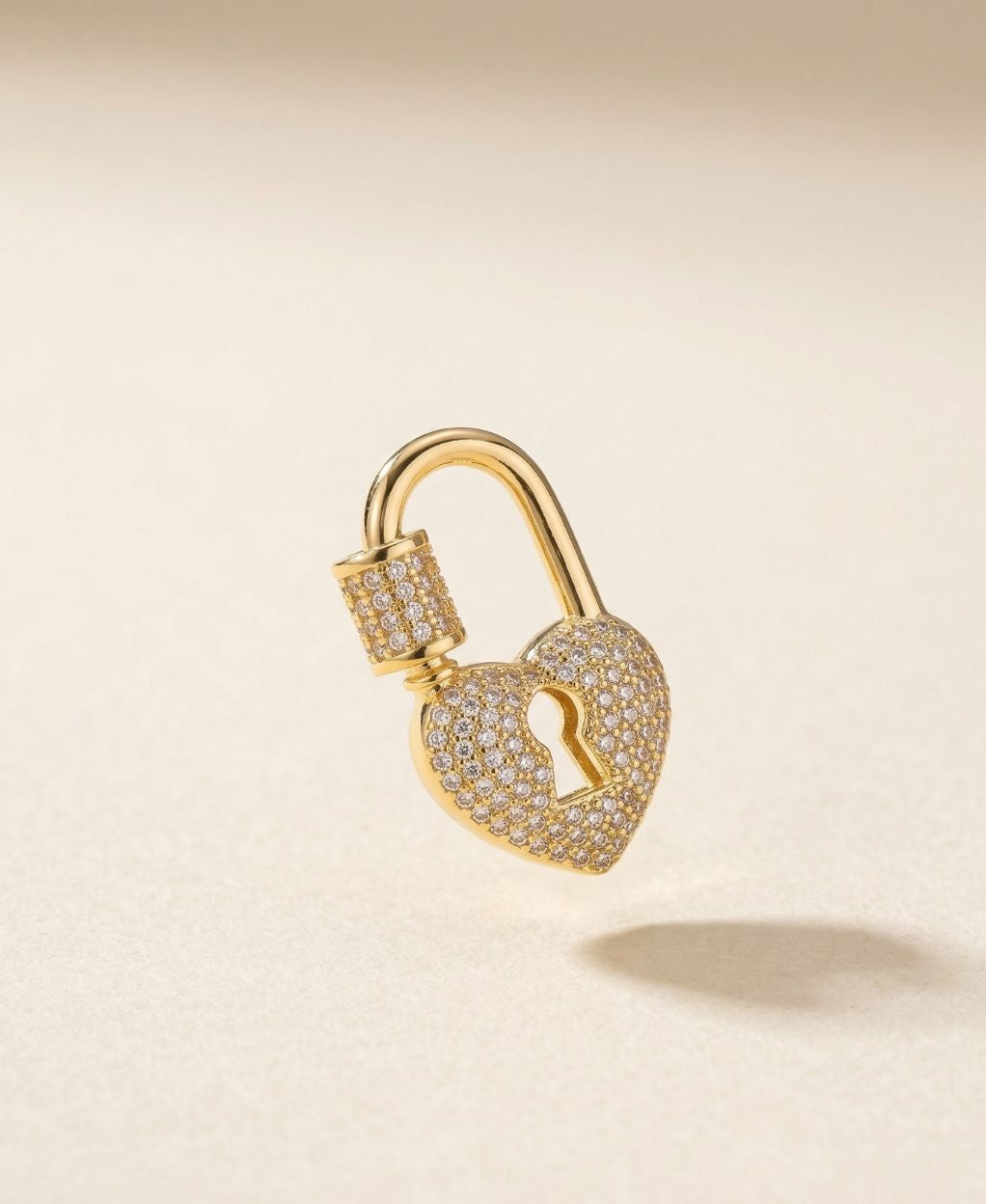 Gold padlock-shaped earring on a beige background
