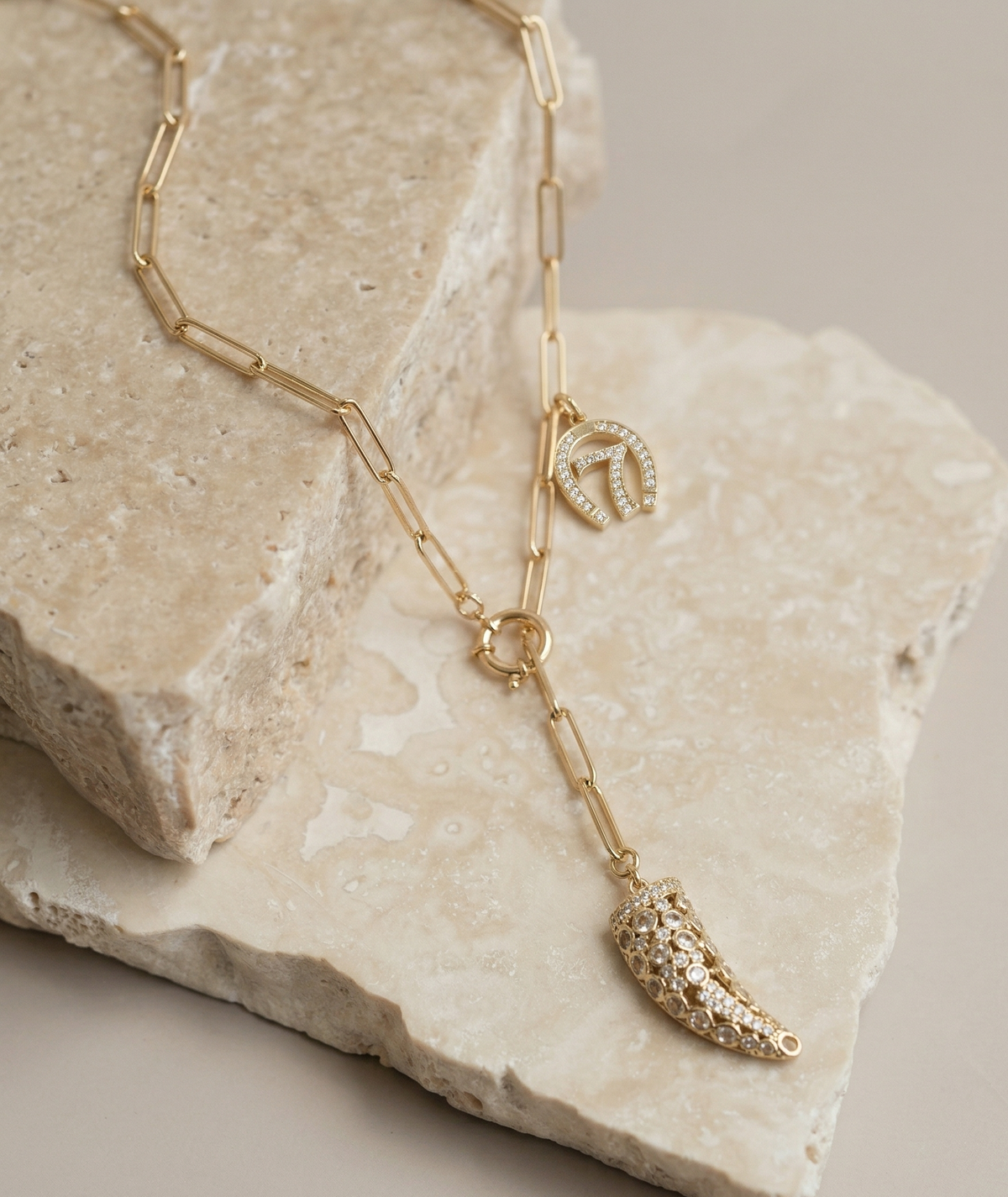 Gold necklace with leaf-shaped pendant on a stone surface