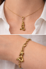 Gold mermaid pendant necklace and bracelet on a person wearing a white shirt.