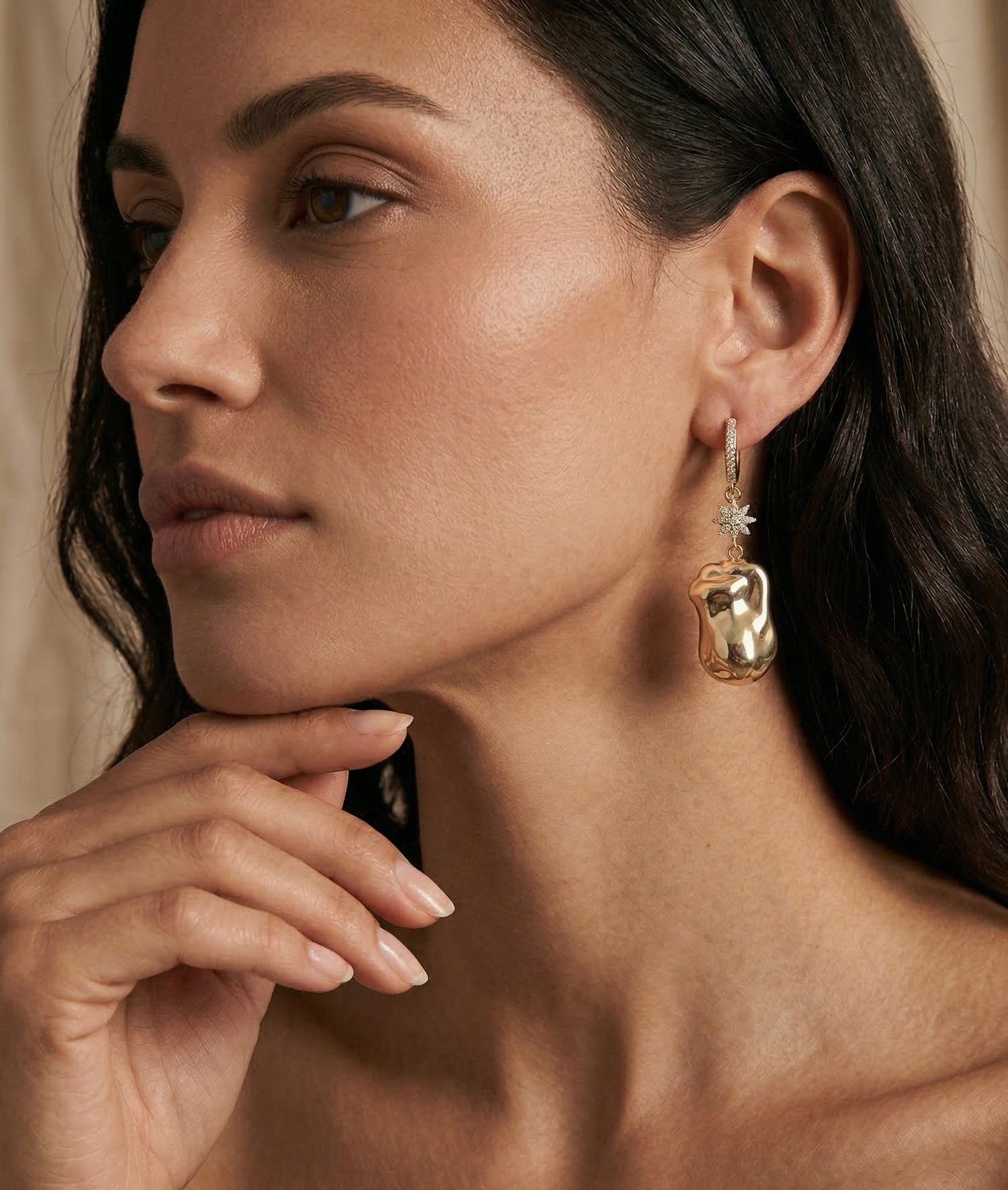 Woman wearing gold hoop earrings with a neutral background