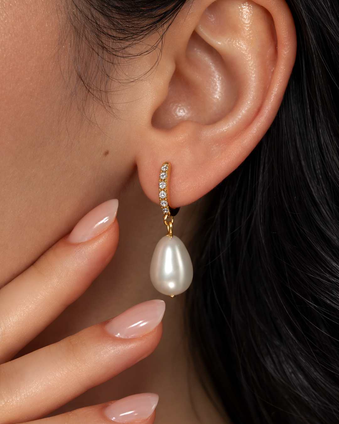 Pearl earring worn by a person with a close-up of the ear 