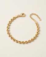 Gold heart-shaped bracelet on a beige background