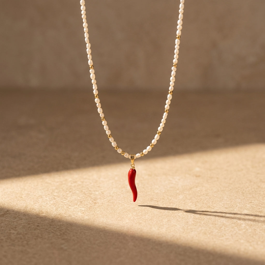 Pearl necklace with a red chili pepper pendant on a beige background