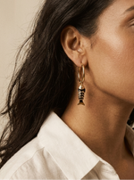 Close-up of a person wearing fish hoop earrings with a neutral background