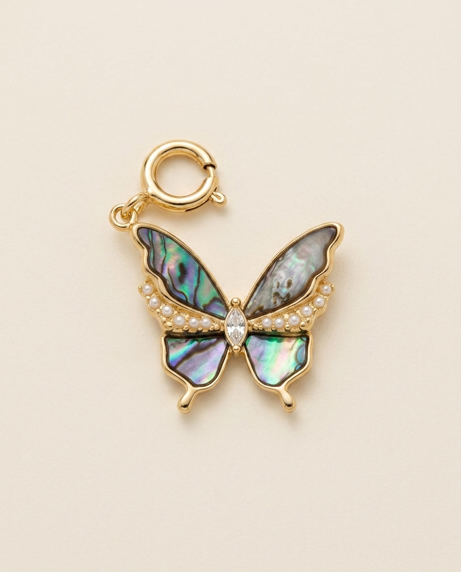 Butterfly charm with abalone shell and pearl details on a beige background