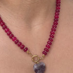 Deep red jade beaded necklace with gold ring clasp and banded amethyst heart pendant, worn on neck with white tank top