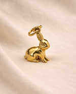 Gold rabbit charm on a beige fabric background