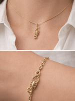 Gold necklace and bracelet with a scorpion design worn on a person's neck and wrist.