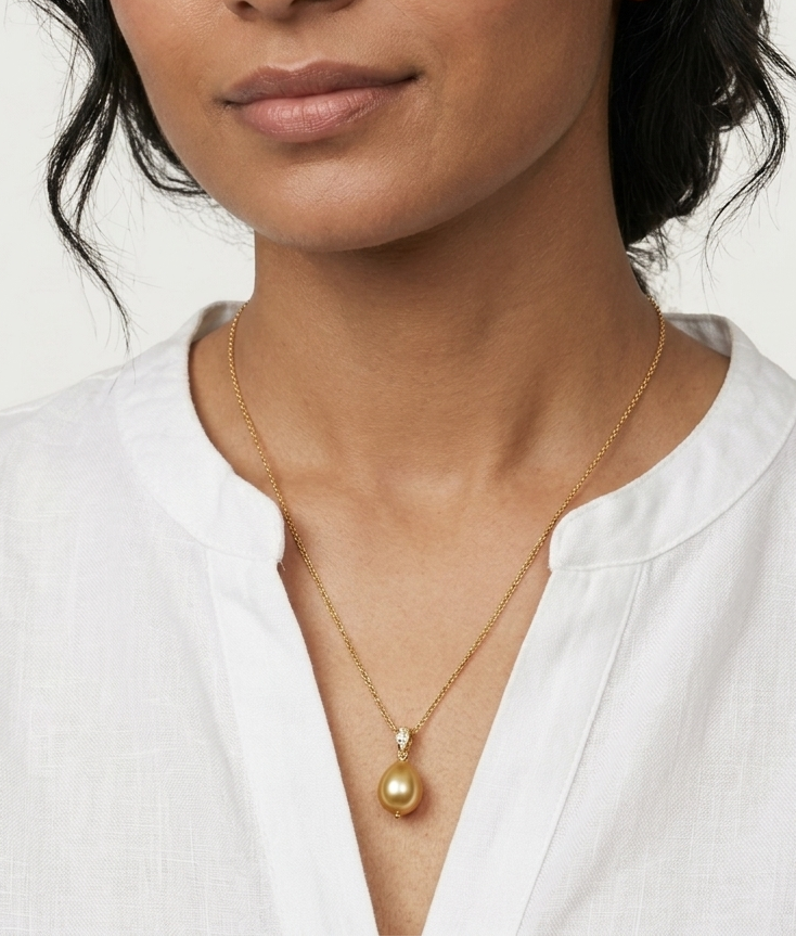Woman wearing a gold necklace with a white shirt on a plain background