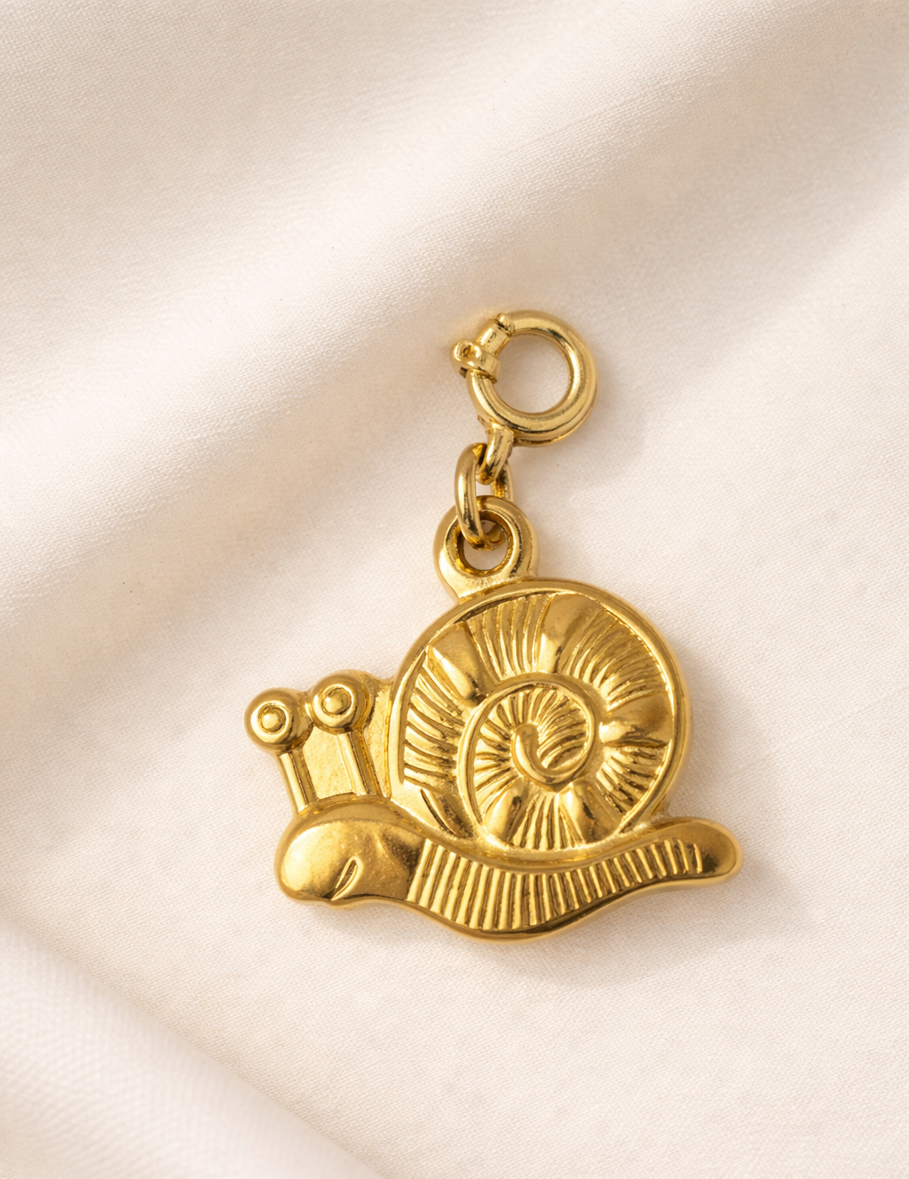 Gold snail-shaped charm on a beige background