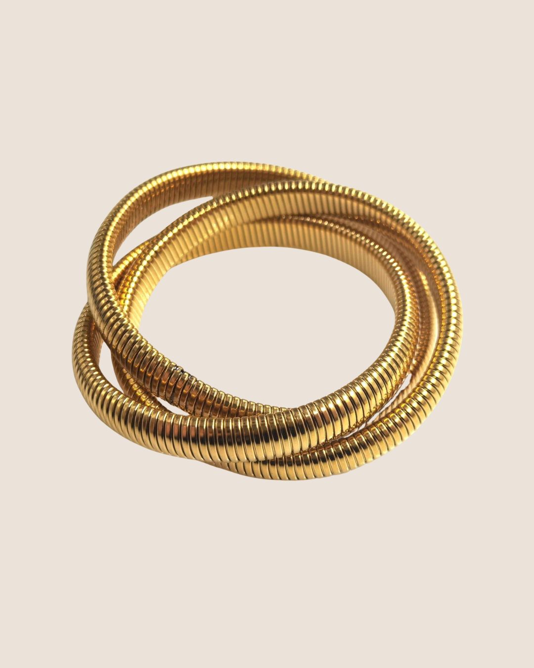 Three gold snake stretcg bracelets on a beige background