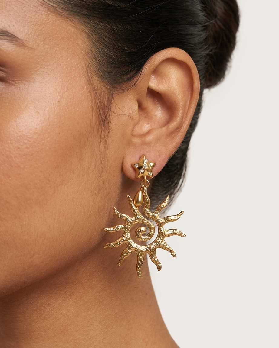 Gold sun-shaped earring worn by a person on a plain background
