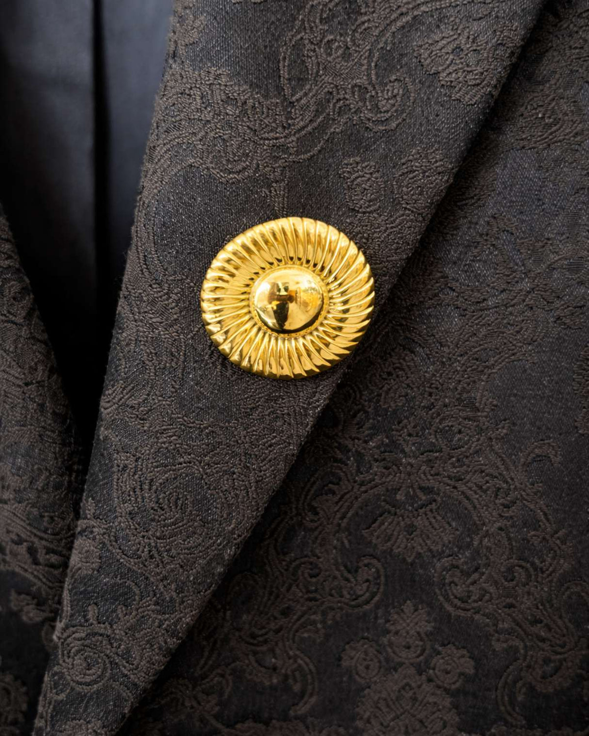 Close-up of a black textured fabric with a gold button