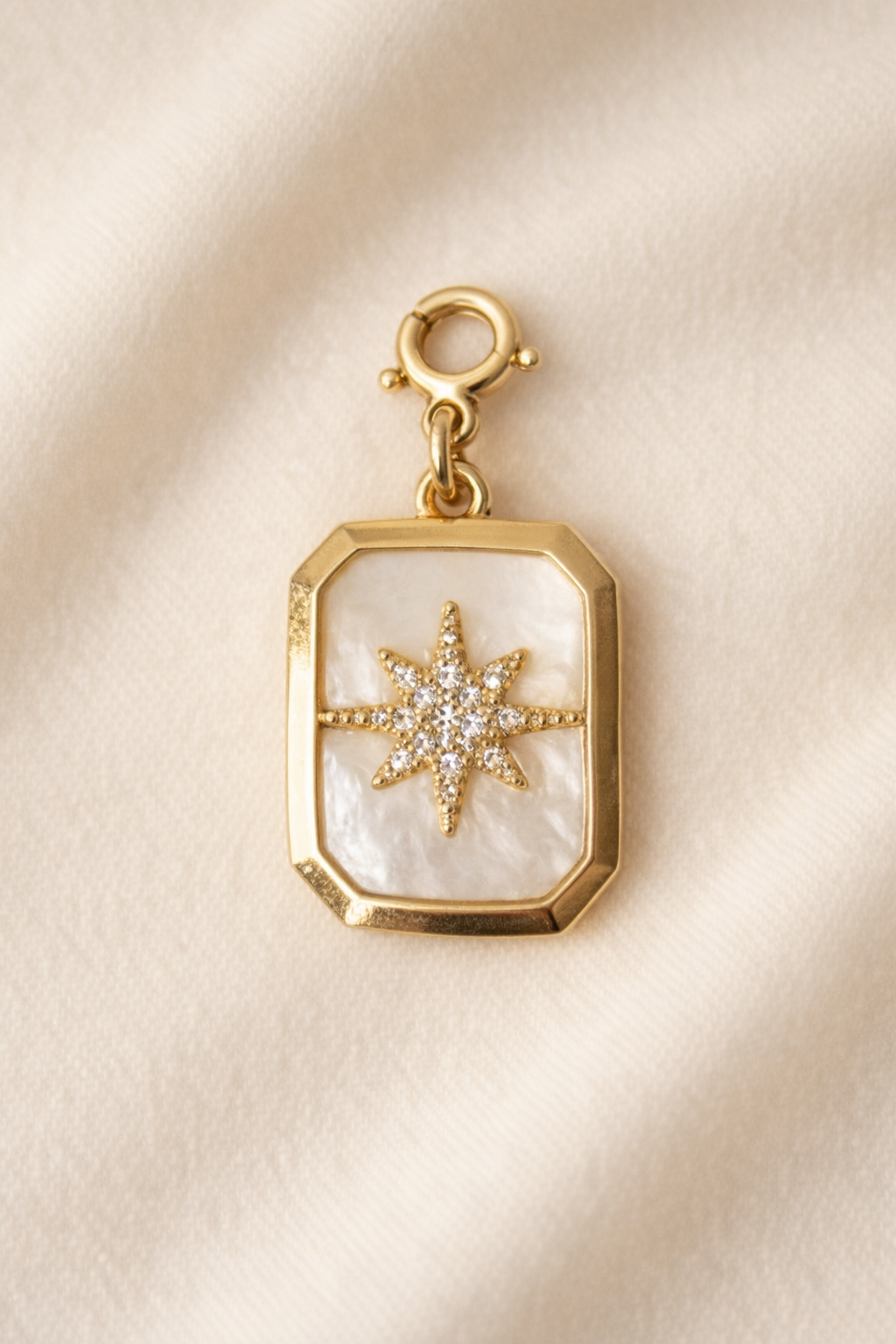 Gold charm with star design on a beige background