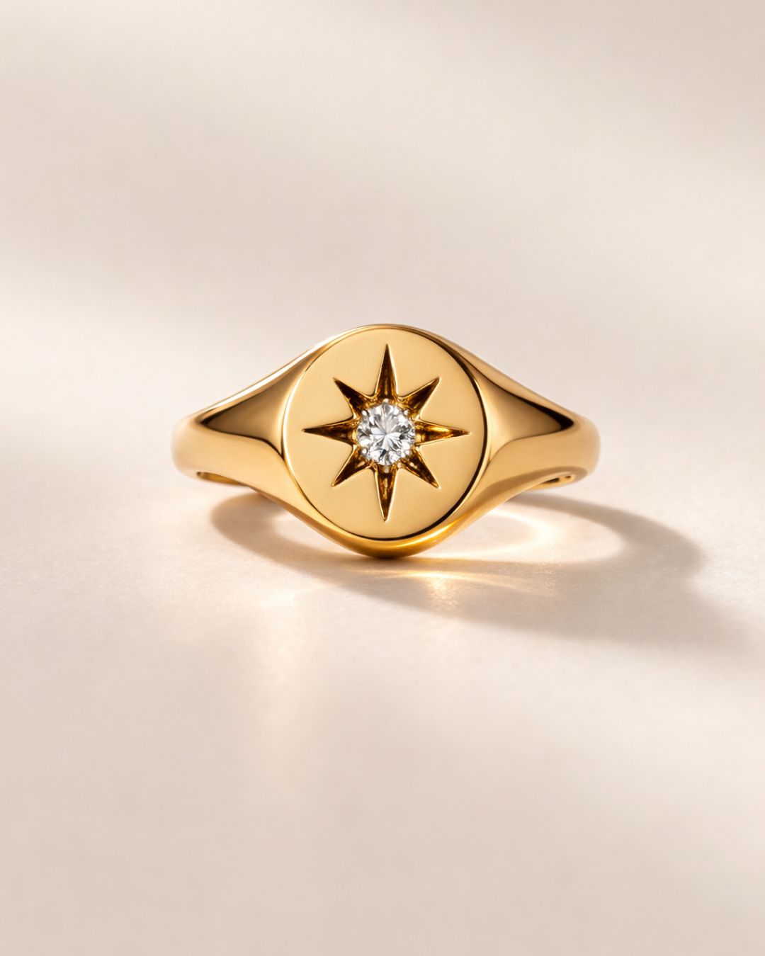 Gold ring with star design and diamond on a beige background