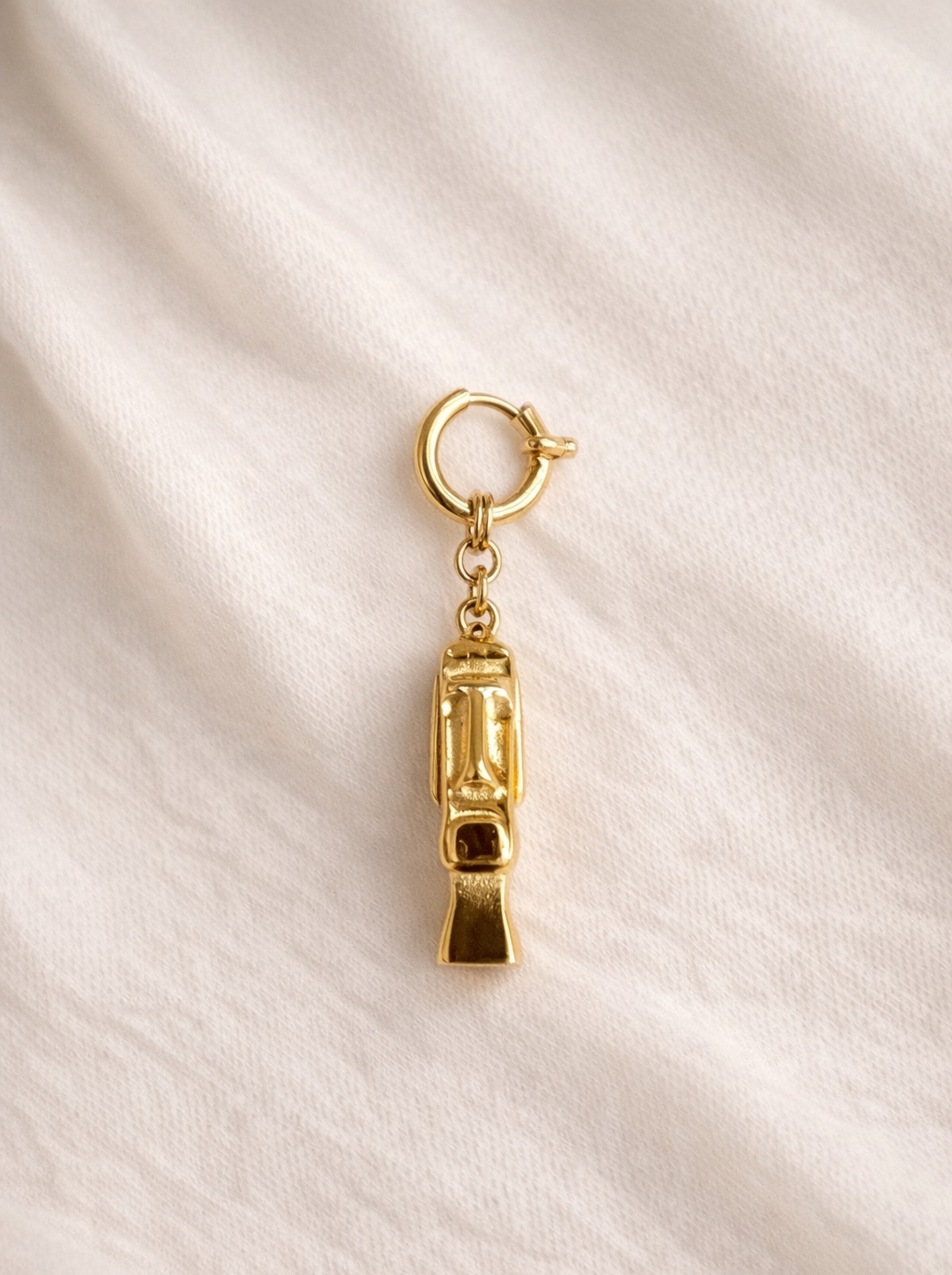 Gold charm on a beige fabric background