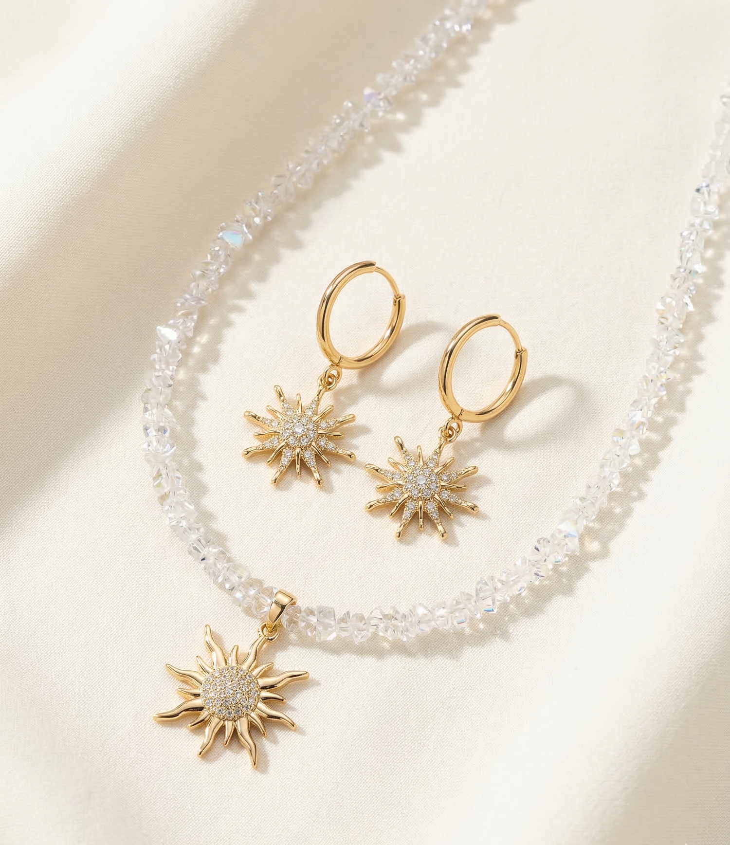 Gold sun-shaped earrings with clear stones on a beige background