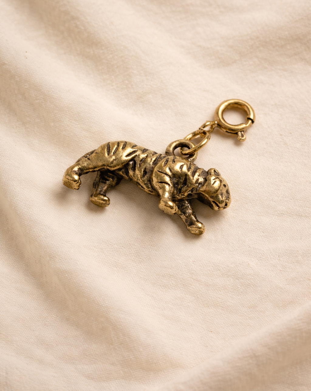 Gold tiger charm on a beige fabric background