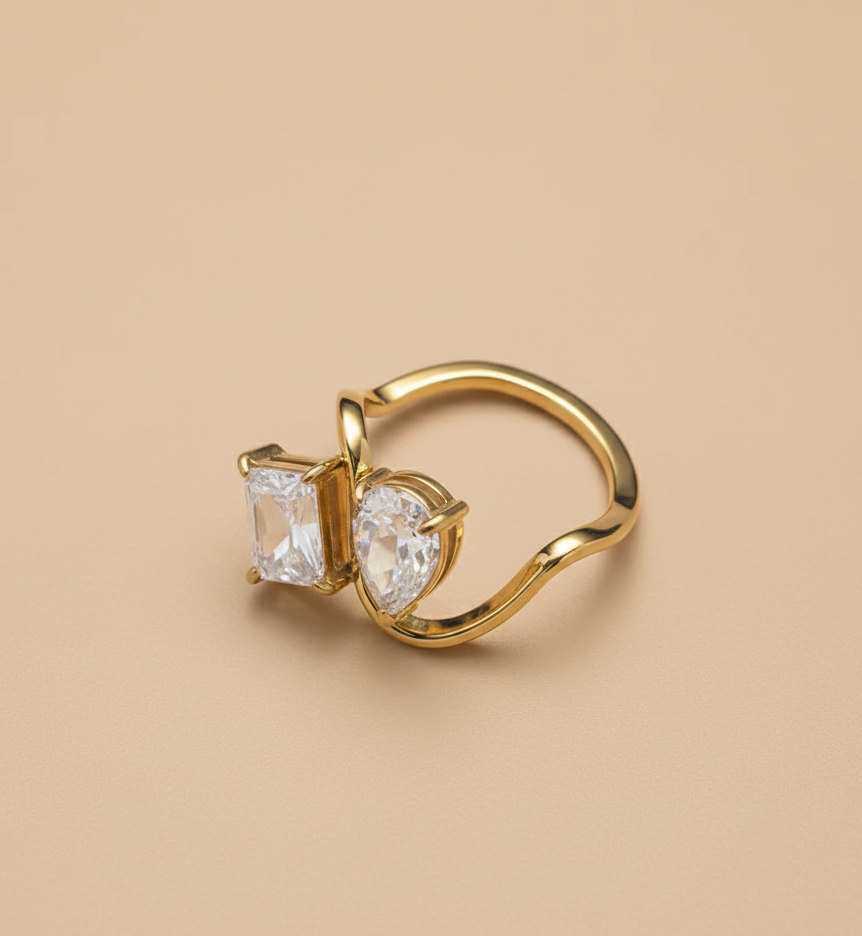 Gold ring with two clear gemstones on a beige background