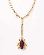 Gold necklace with a beetle pendant on a white background