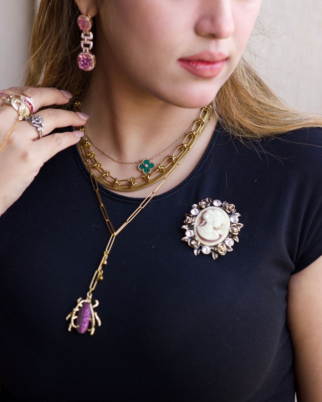 Close-up of a person wearing gold jewelry with a brooch on a plain background