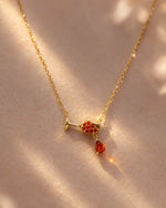 Gold necklace with a red gemstone pendant on a beige background