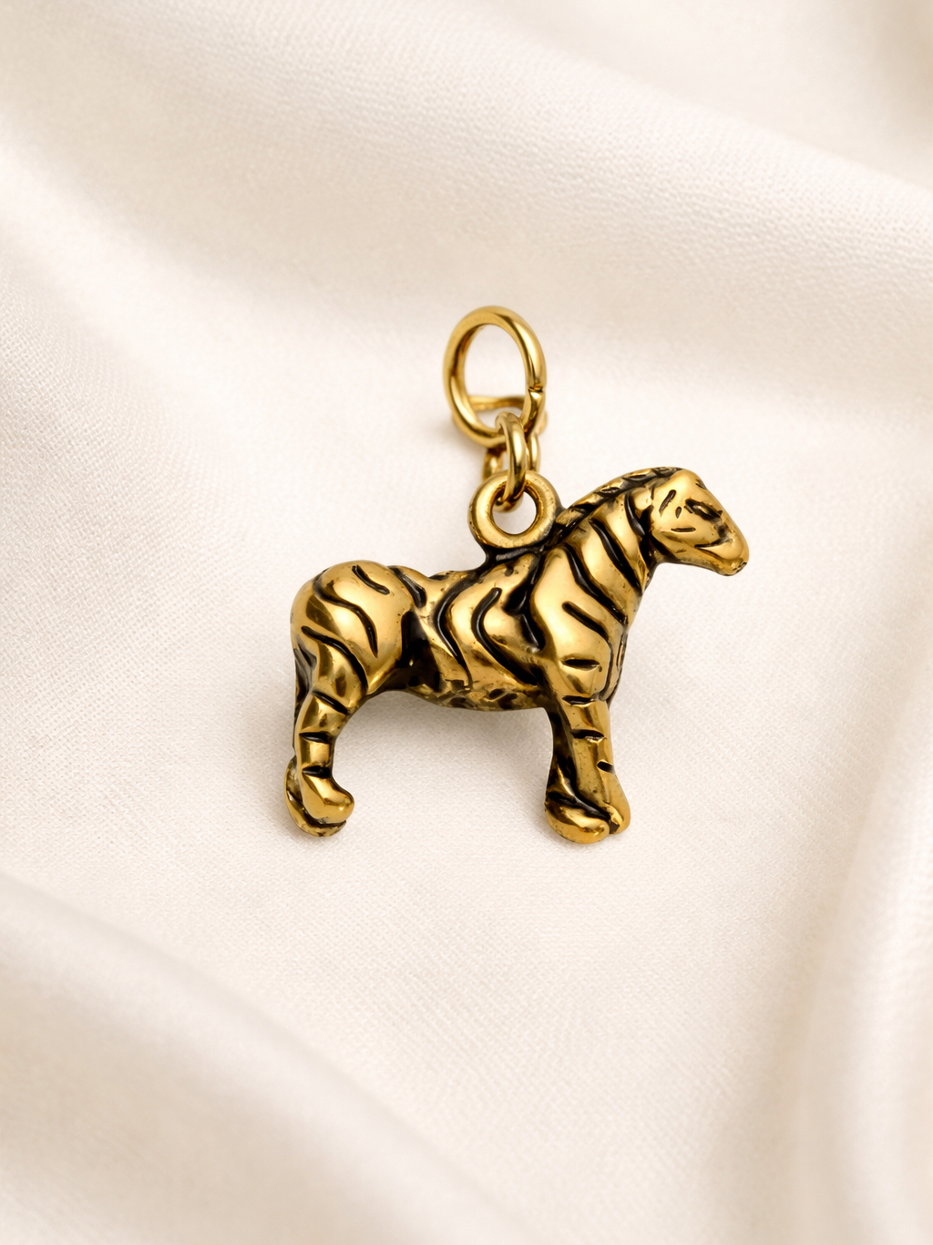 Gold zebra charm on a beige satin background